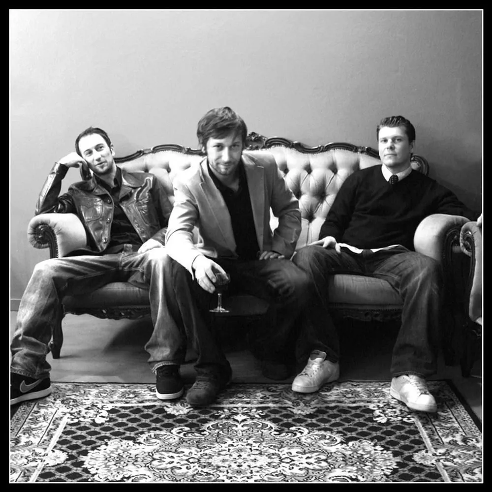Les trois membres de Smooth assis sur un canapé, photo en noir et blanc