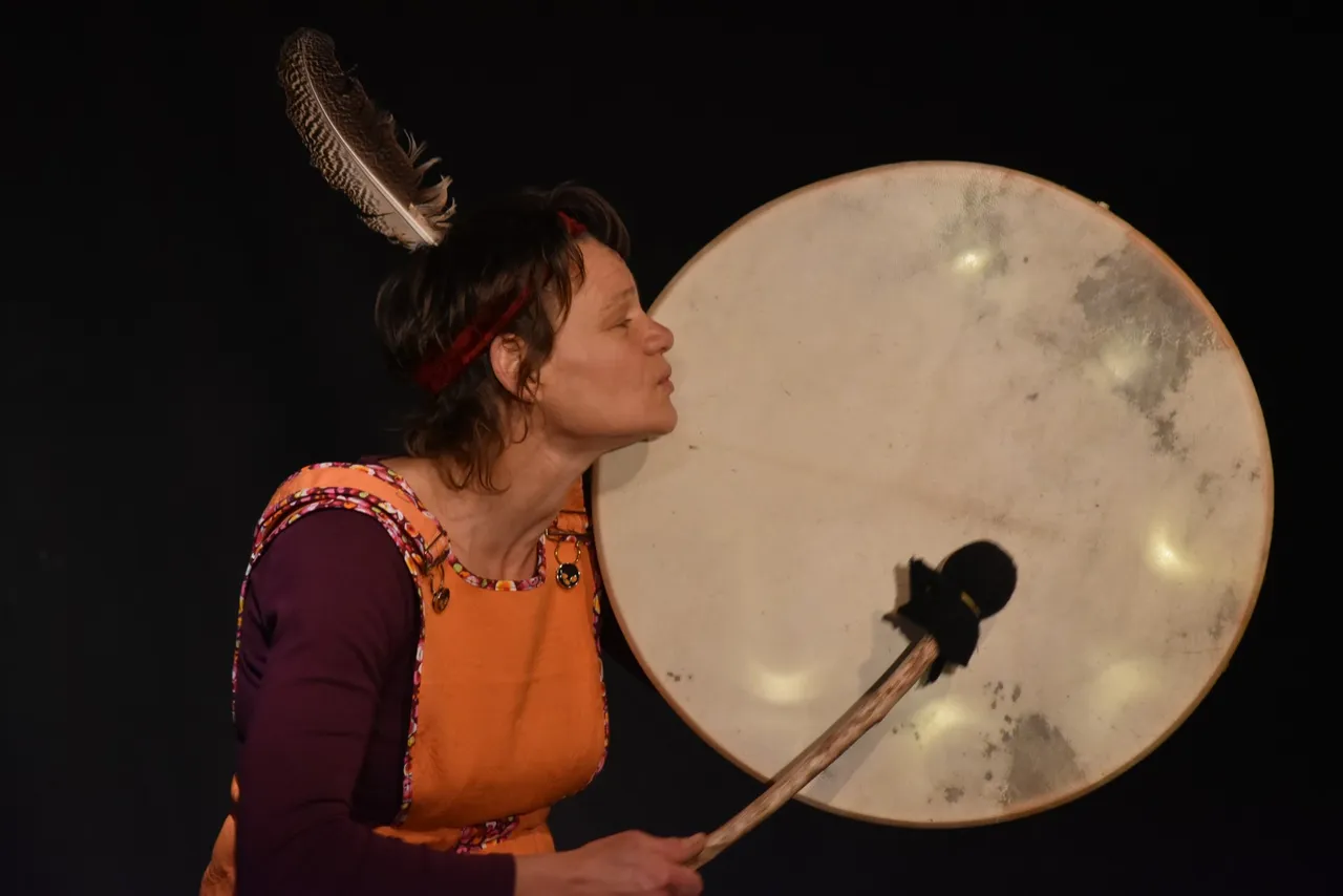 Une comédienne de la Cie Pépaloma en costume, jouant d'un grand tambour sur cadre