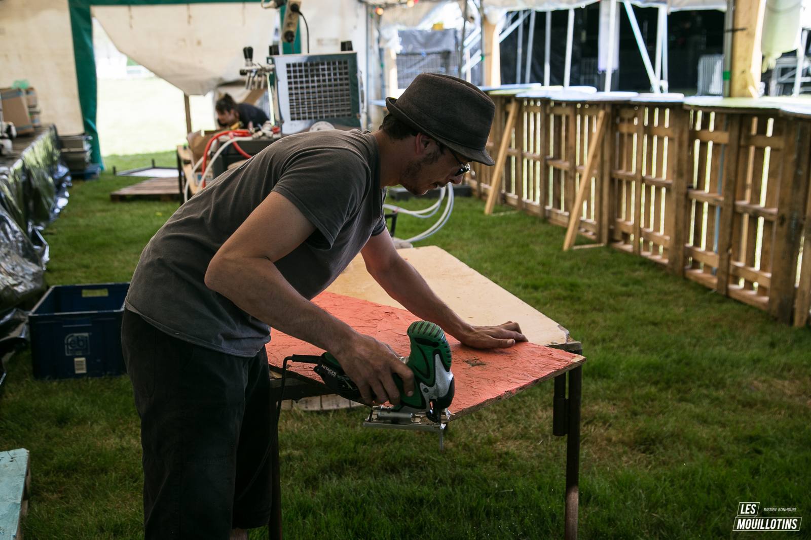 Un bénévole découpe un panneau de bois à la scie sauteuse pendant le montage du festival
