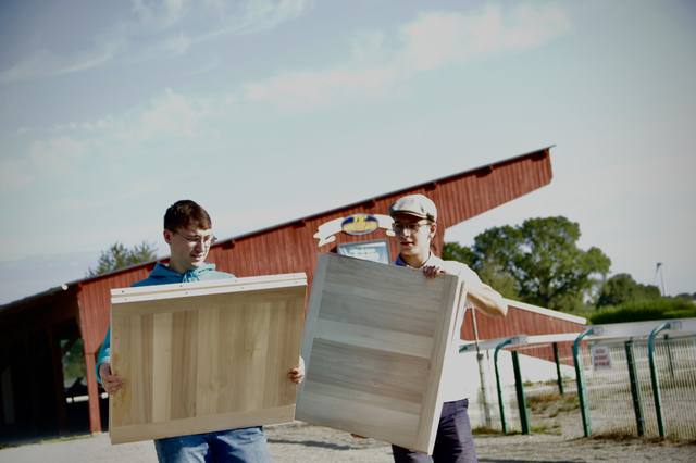 Deux bénévoles portent les planches de jeu avant le tournoi - photo AMAC / Les Mouillotins