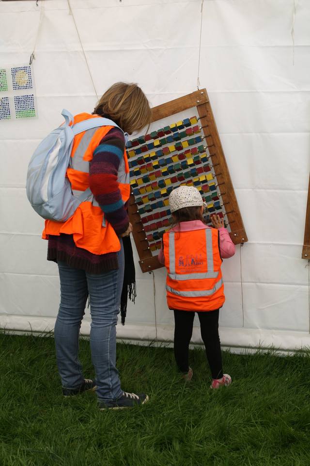 Une bénévole accompagne un enfant devant un jeu mural - photo Clara Mainguené