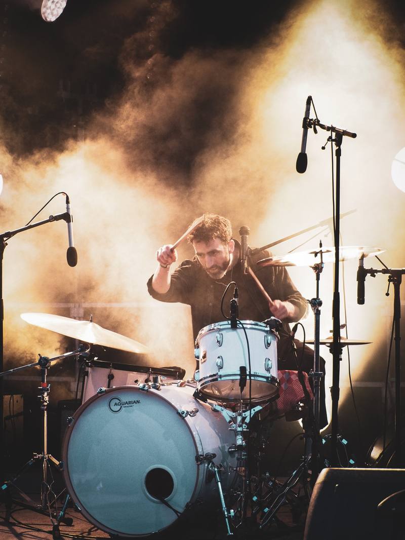 Un batteur sur scène dans la fumée et la lumière dorée - photo Joris