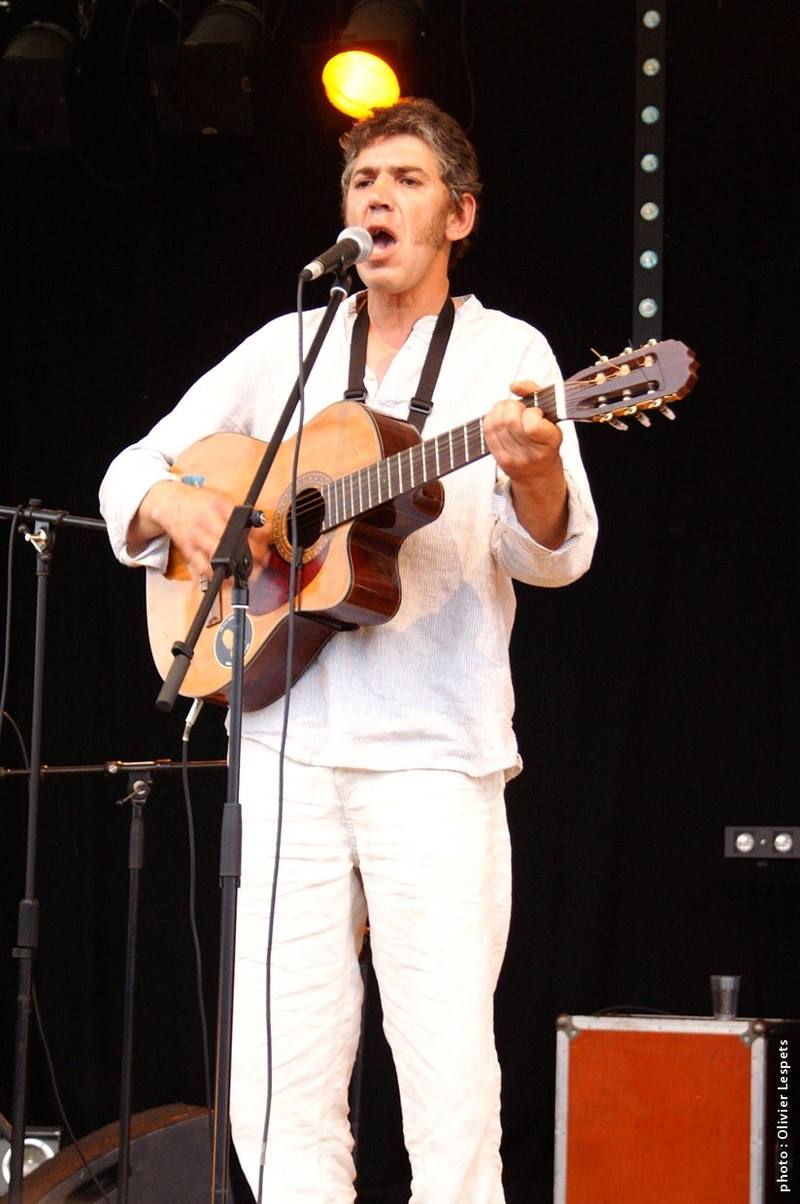 Un chanteur-guitariste en blanc sur scène - photo Olivier Lespets