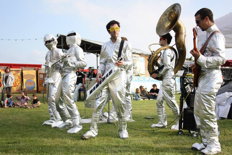 Une fanfare en combinaisons argentées joue sur l'herbe - photo AMAC / Les Mouillotins