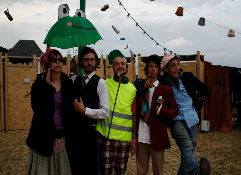 Festivaliers costumés et bénévole en gilet jaune sous les décors du site - photo AMAC / Les Mouillotins