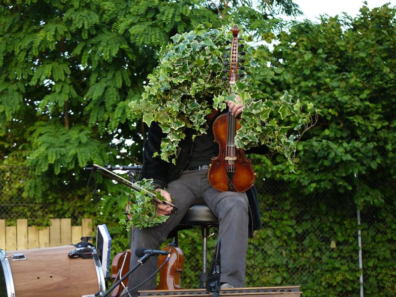 Un violoniste homme-orchestre joue dans la verdure - photo AMAC / Les Mouillotins